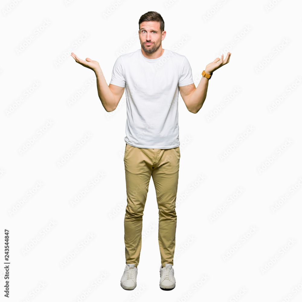 Handsome man wearing casual white t-shirt clueless and confused expression with arms and hands raised. Doubt concept. Handsome man wearing casual white t-shirt clueless and confused expression with arms and hands raised. Doubt concept.