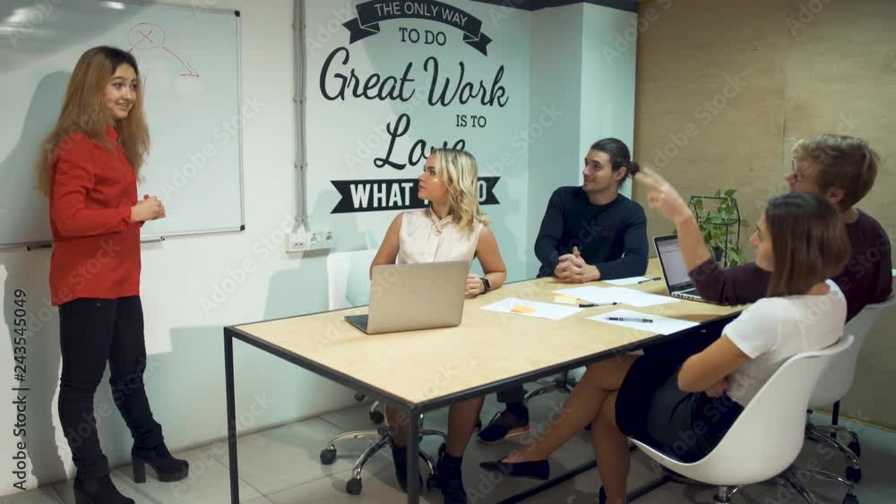 Young woman shows details on whiteboard and propose new startup ideas causing a strong reaction from colleagues Young woman shows details on whiteboard and propose new startup ideas causing a strong reaction from colleagues