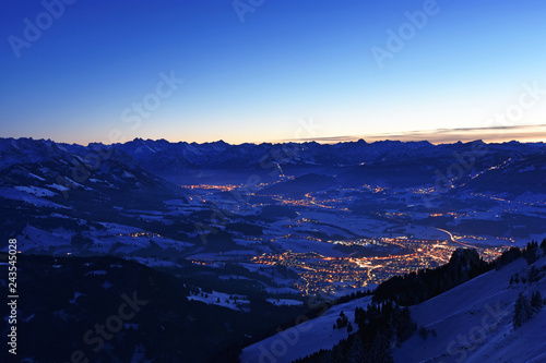 Wallpaper Mural City night lights of Sonthofen and Oberstdorf (Allgaeu Alps, Bavaria, Germany) after sunset from the summit of Gruenten mountain in winter. Alpine landscape during blue hour. Copy space. Torontodigital.ca