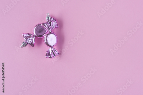 Two pink candies - christmas tree decoration on pastel pink paper background. Minimal Christmas concept or sweet valentine day with copy space. Top view. Template for greeting card or a poster.