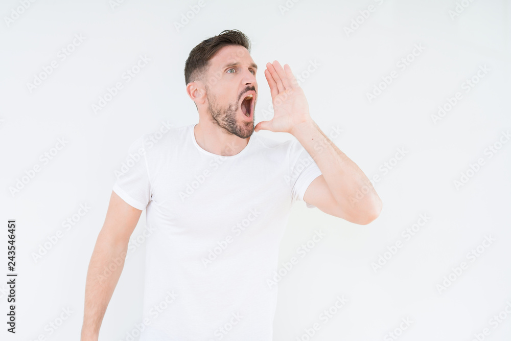 Young handsome man wearing casual white t-shirt over isolated background shouting and screaming loud to side with hand on mouth. Communication concept. Young handsome man wearing casual white t-shirt over isolated background shouting and screaming loud to side with hand on mouth. Communication concept.