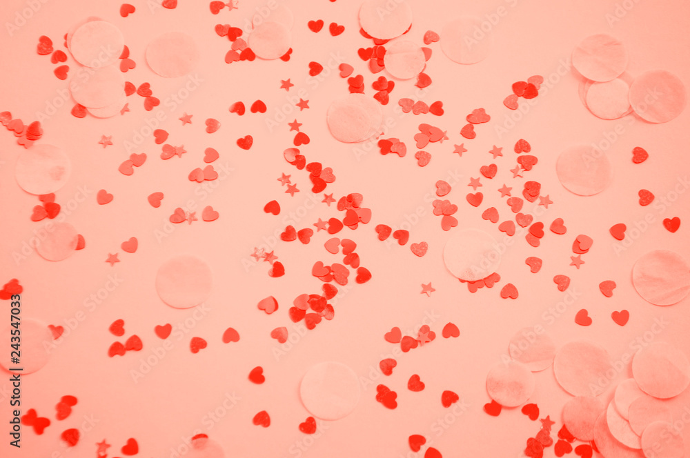 Defocused and blurred beautiful heart and stars shaped red confetti on coral background. Color of 2019 concept.