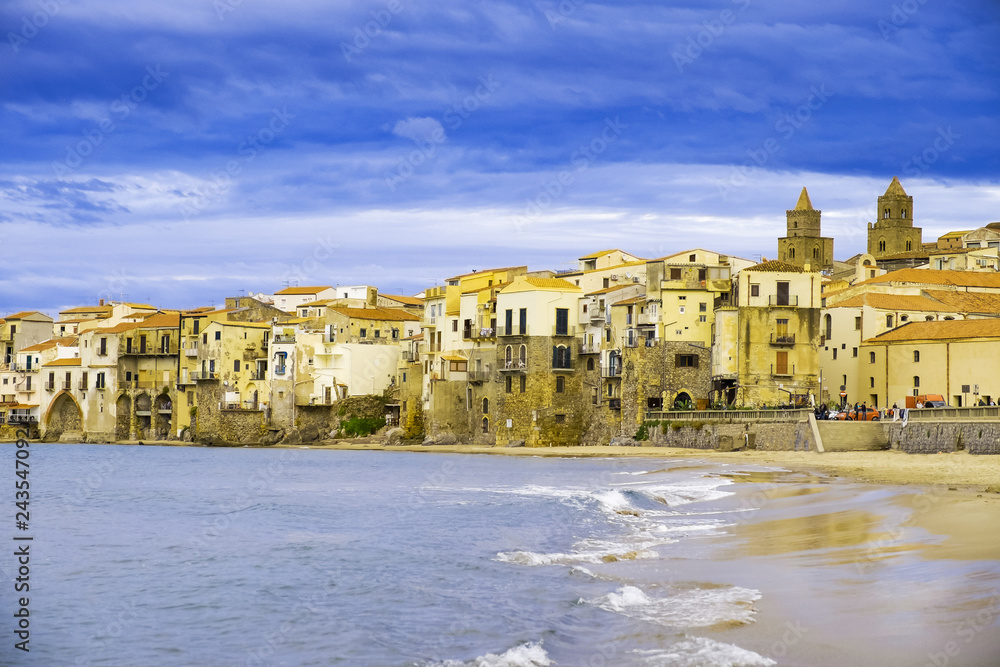 Houses along the shoreline and cathedral in background Cefalu Sicily.