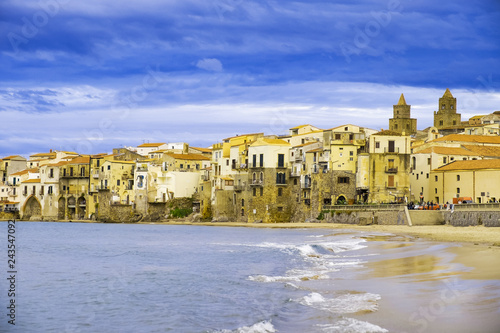 Houses along the shoreline and cathedral in background Cefalu Sicily.