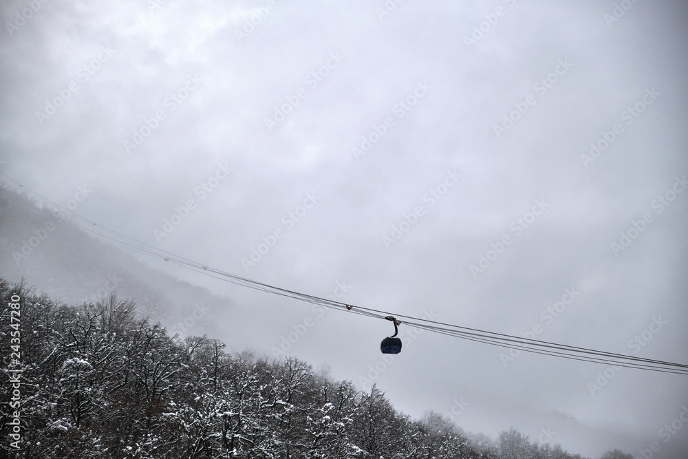 Cable car in winter. Over the mountains, forest, field. Ski resort. It's cold and beautiful. Trees in the snow. Fog, drizzle, ice. Blue and white. Sky. Cable car in winter. Over the mountains, forest, field. Ski resort. It's cold and beautiful. Trees in the snow. Fog, drizzle, ice. Blue and white. Sky.