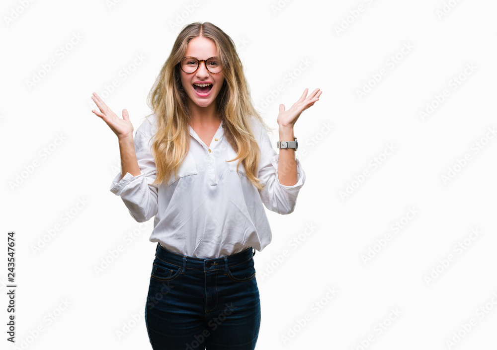 Young beautiful blonde business woman wearing glasses over isolated background celebrating crazy and amazed for success with arms raised and open eyes screaming excited. Winner concept Young beautiful blonde business woman wearing glasses over isolated background celebrating crazy and amazed for success with arms raised and open eyes screaming excited. Winner concept