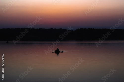Silhouette of a man which floating on a boat on the sea at sunset time.