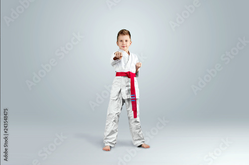Creative background, baby in white kimono on a light background. The concept of martial arts, karate, sports since childhood, discipline.