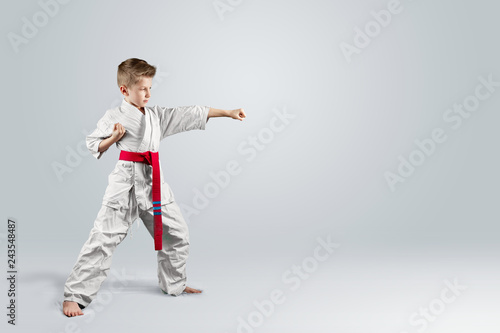 Creative background, baby in white kimono on a light background. The concept of martial arts, karate, sports since childhood, discipline.