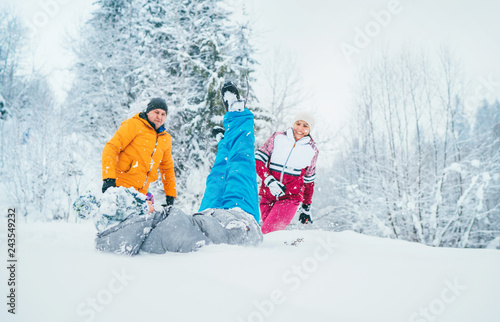 Mother and father family fooling in snow forest by throwing their little son to snowdrift