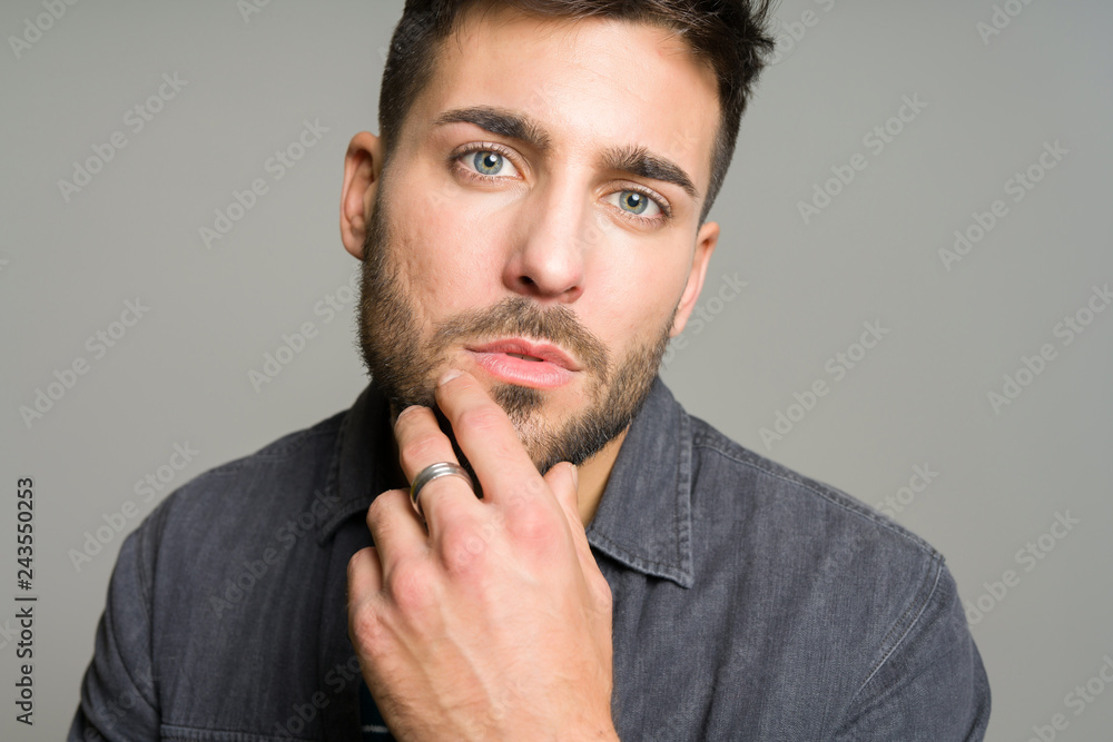 Young handsome man possing and modeling over grey isolated background