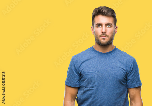 Young handsome man over isolated background with serious expression on face. Simple and natural looking at the camera.