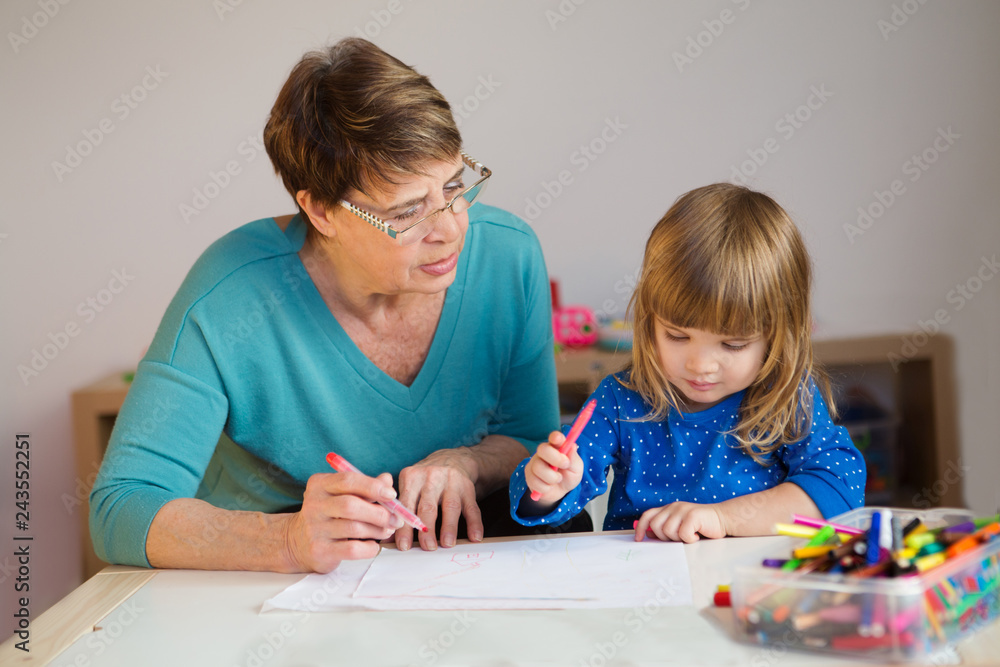 Fototapeta premium Happy family. grandmother draws with little child girl together.