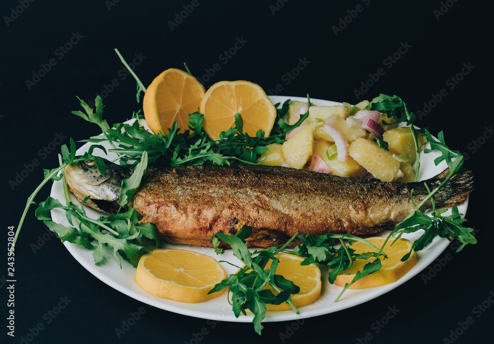 Grilled fish served with potato, arugula and lemon Grilled fish served with potato, arugula and lemon