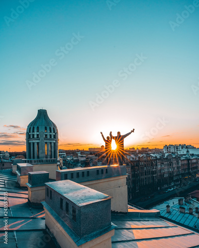 couple silhouettes stay on the rooftop in lights of sunset in historical city center of Saint-Petersburg