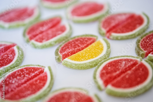 Marmalade in the form of slices of watermelon and lime lies on a white surface. Stand out from the crowd photo
