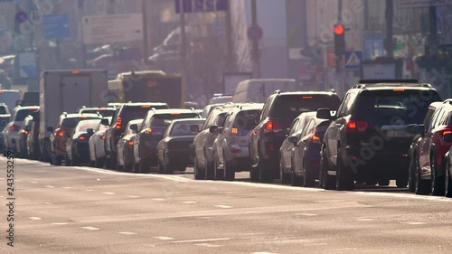 Blurred street shot of cars standing in traffic jam and slowly moving on city background.