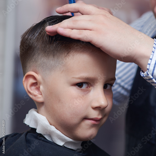 Boy getting haircut by barber in barbershop