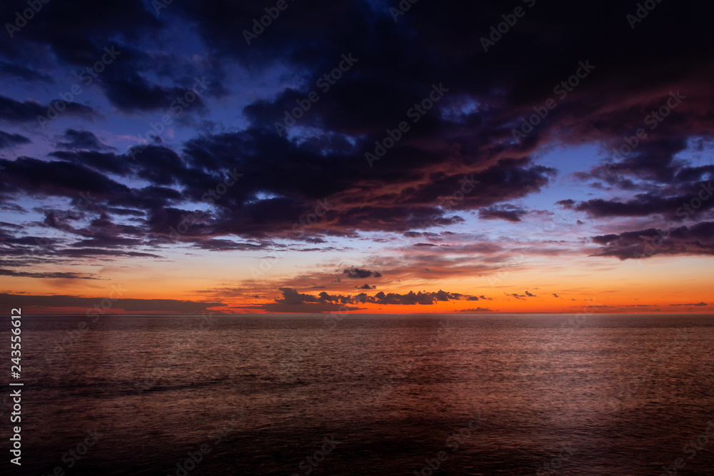 Colorful sunset with dramatic cloudy sky over calm sea in Meloneras, Gran Canaria. Lovely twilight by the ocean. Background texture, nature beauty concepts