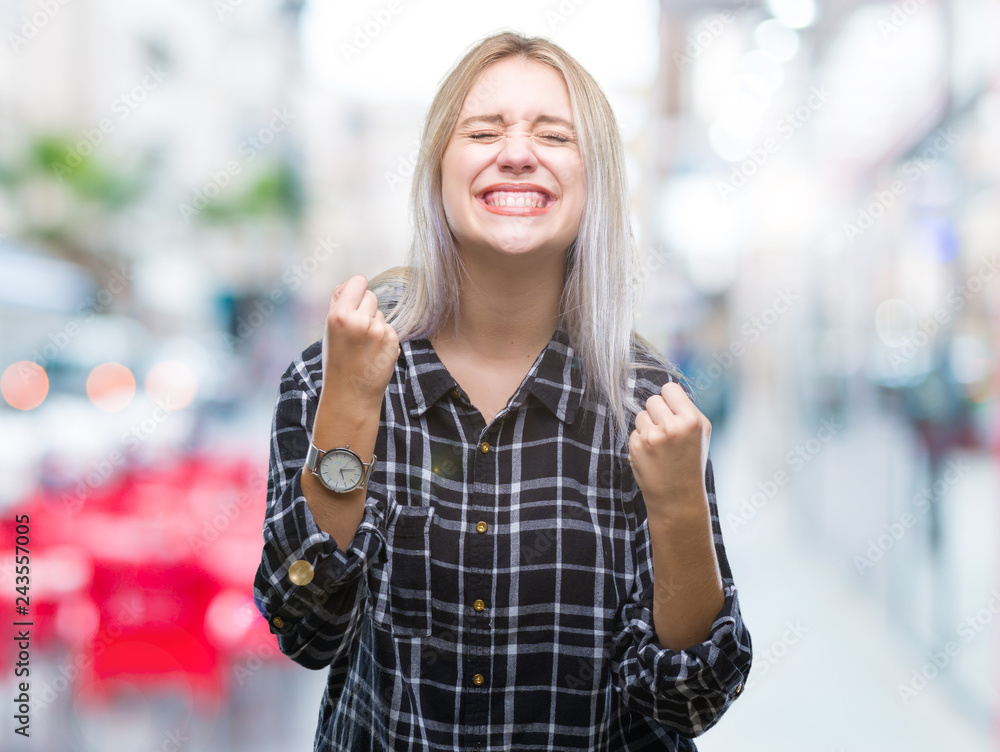 Young blonde woman over isolated background very happy and excited doing winner gesture with arms raised, smiling and screaming for success. Celebration concept.
