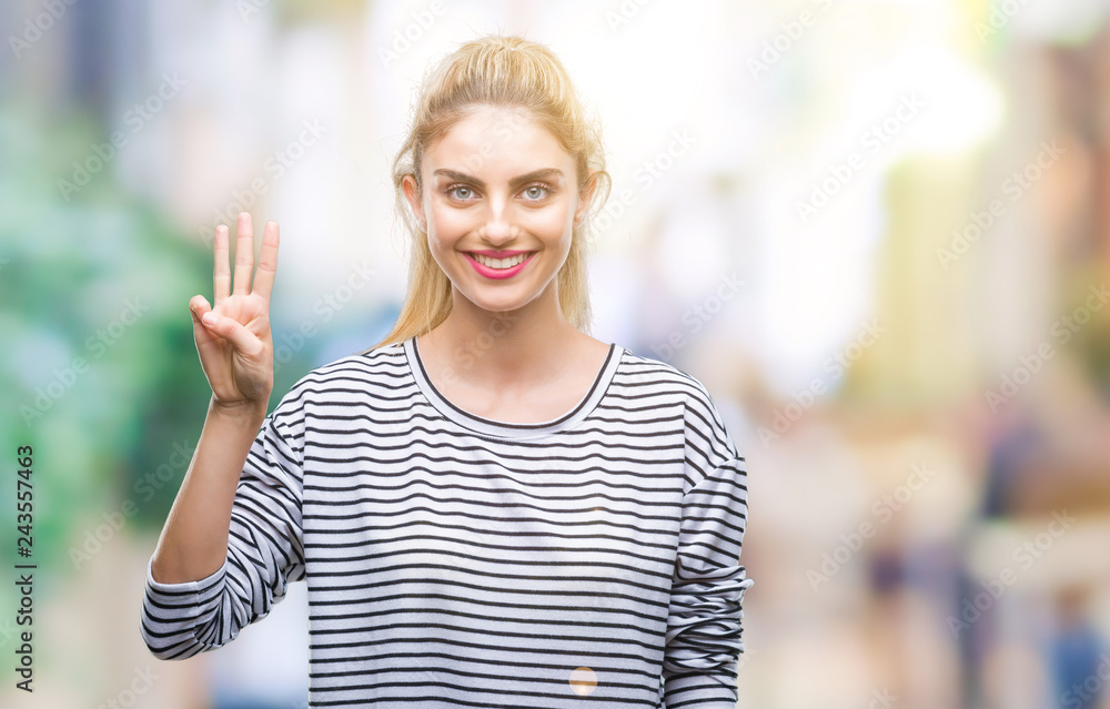 Young beautiful blonde woman wearing stripes sweater over isolated background showing and pointing up with fingers number three while smiling confident and happy.