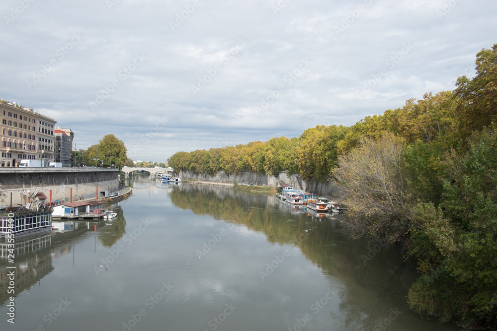 River with boats on berth, embankment full of trees