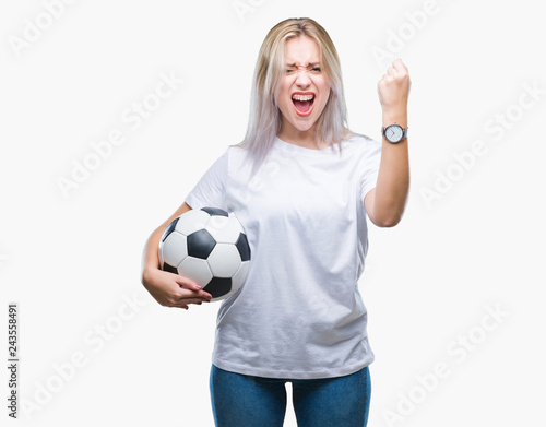 Young blonde woman holding soccer football ball over isolated background annoyed and frustrated shouting with anger, crazy and yelling with raised hand, anger concept