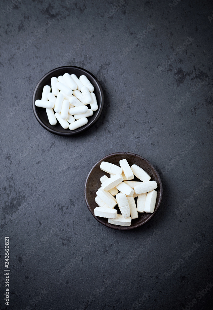 Glutamine and BCAA amino acids. Nutrition for bodybuilding. Fitness supplements on black stone background. Top view. Copy space. Glutamine and BCAA amino acids. Nutrition for bodybuilding. Fitness supplements on black stone background. Top view. Copy space.