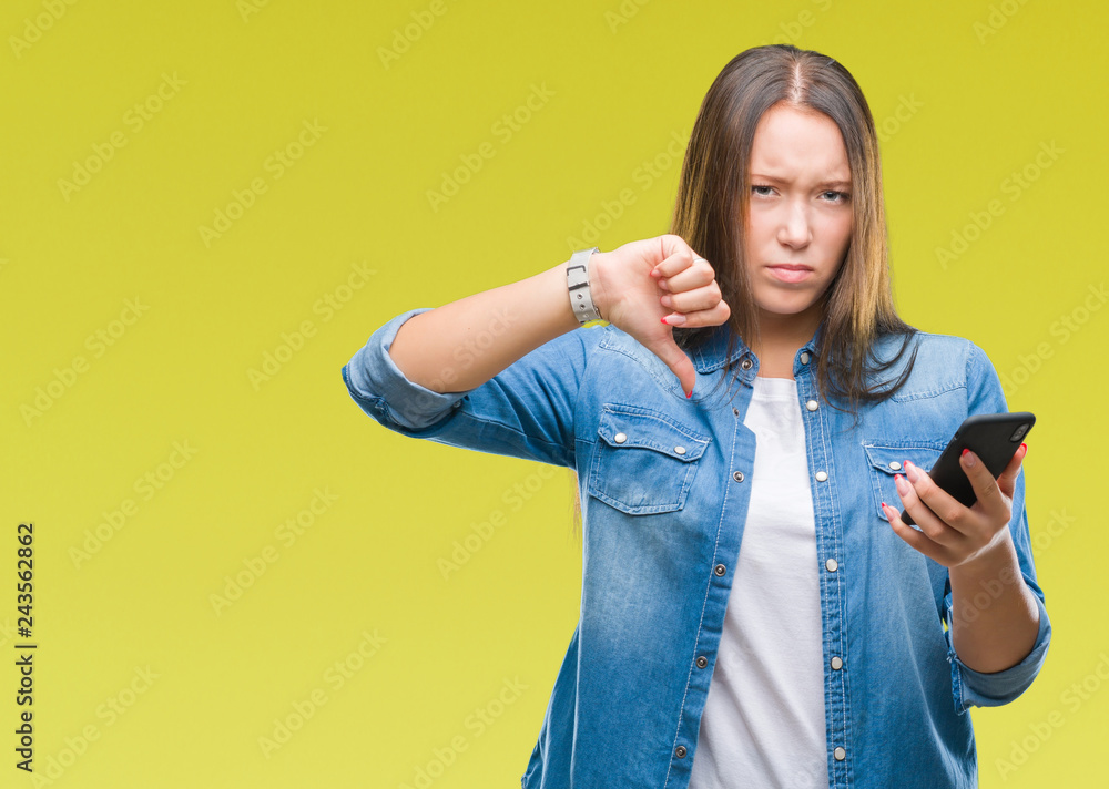 Young beautiful caucasian woman texting sending message using smartphone over isolated background with angry face, negative sign showing dislike with thumbs down, rejection concept Young beautiful caucasian woman texting sending message using smartphone over isolated background with angry face, negative sign showing dislike with thumbs down, rejection concept