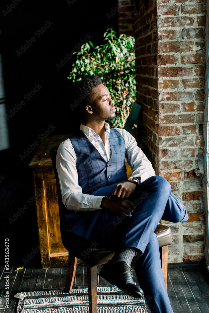 Obraz premium Close up portrait of handsome young male fashion model sitting by a window