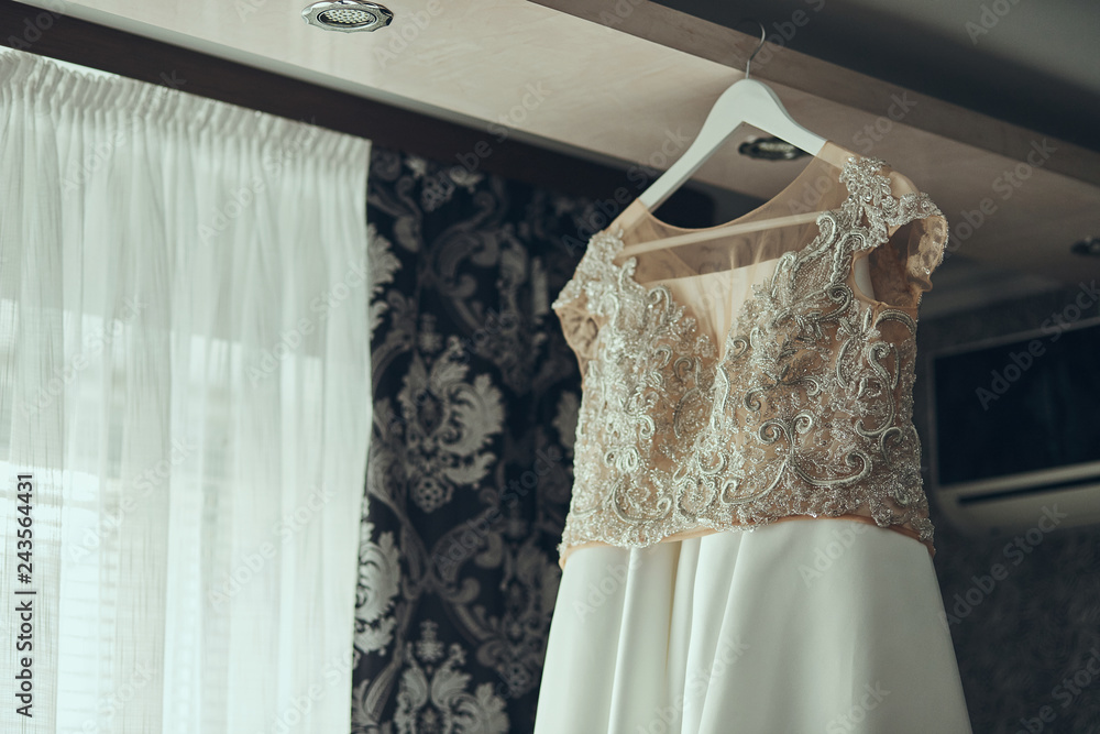 beautiful wedding dress hanging in the room, woman getting ready before ceremony beautiful wedding dress hanging in the room, woman getting ready before ceremony