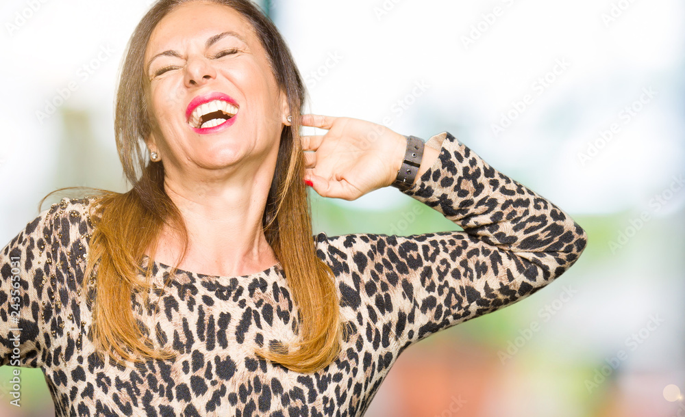 Beautiful middle age woman wearing leopard animal print dress stretching back, tired and relaxed, sleepy and yawning for early morning