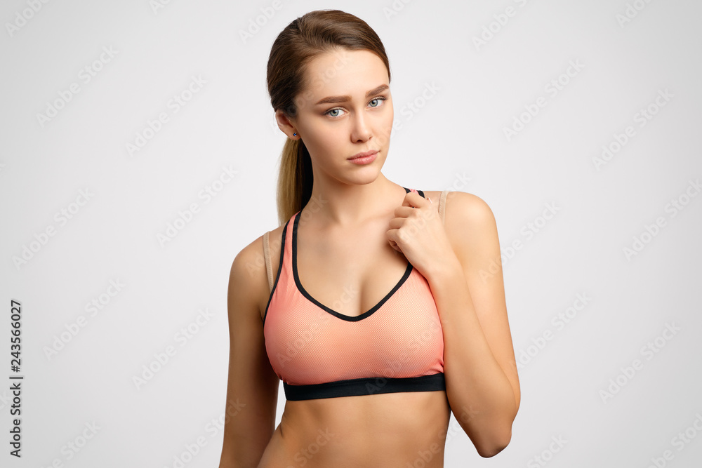 Athletic attractive girl in a sports top defiantly looks into the camera and presses her hand to her chest. The concept of slim figure, sports and fitness, a healthy lifestyle and weight control. Athletic attractive girl in a sports top defiantly looks into the camera and presses her hand to her chest. The concept of slim figure, sports and fitness, a healthy lifestyle and weight control.