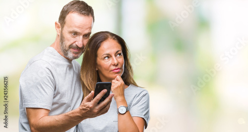 Middle age hispanic couple texting message on smartphone ver isolated background serious face thinking about question, very confused idea © Krakenimages.com