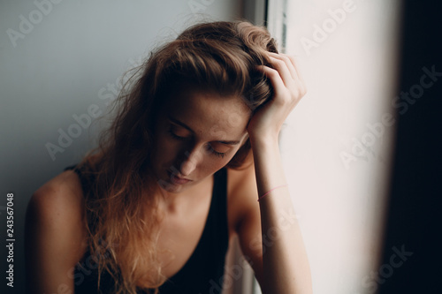 Portrait of young beautiful woman near misted window