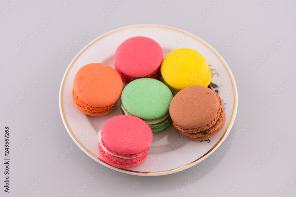 Multi-coloured macarons on a porcelain plate Multi-coloured macarons on a porcelain plate