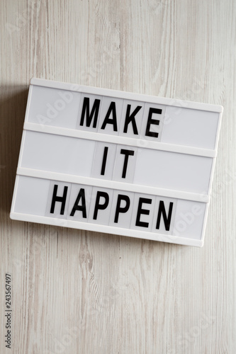 Fototapeta Naklejka Na Ścianę i Meble -  Lightbox with text 'Make it happen' on a white wooden surface, top view. From above, flat lay, overhead. Close-up.