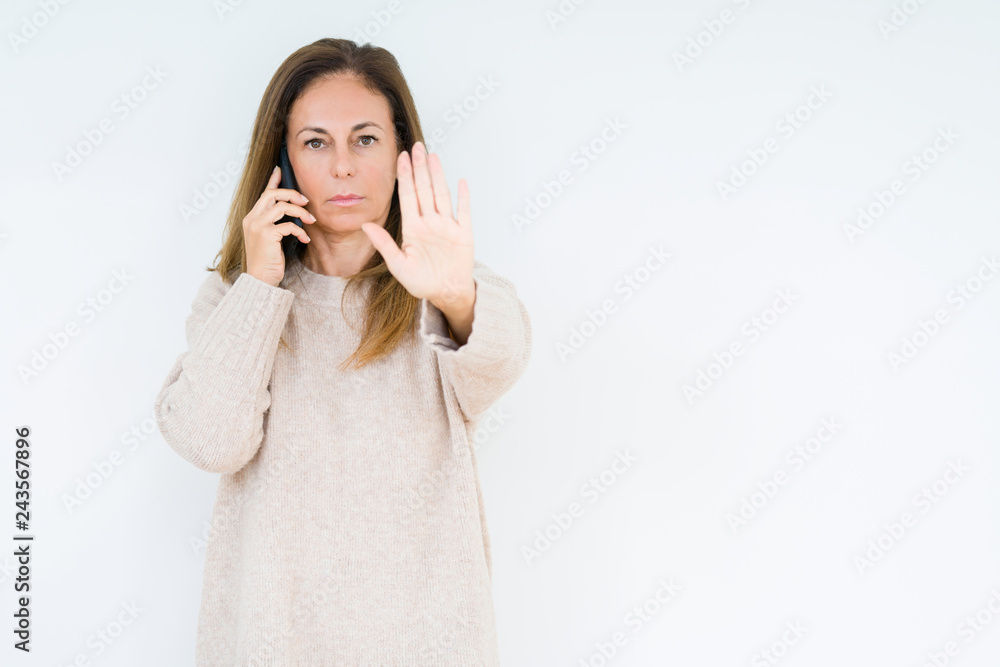 Middle age woman talking on smartphone over isolated background with open hand doing stop sign with serious and confident expression, defense gesture Middle age woman talking on smartphone over isolated background with open hand doing stop sign with serious and confident expression, defense gesture