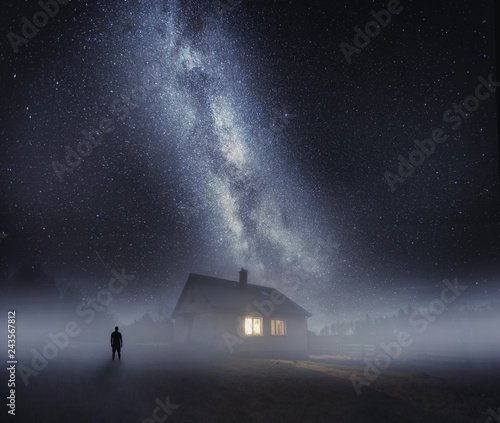 Surreal night landscape with house in fog and human silhouette