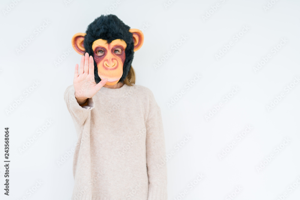 Obraz premium Middle age woman wearing funny and crazy money mask over isolated background with open hand doing stop sign with serious and confident expression, defense gesture