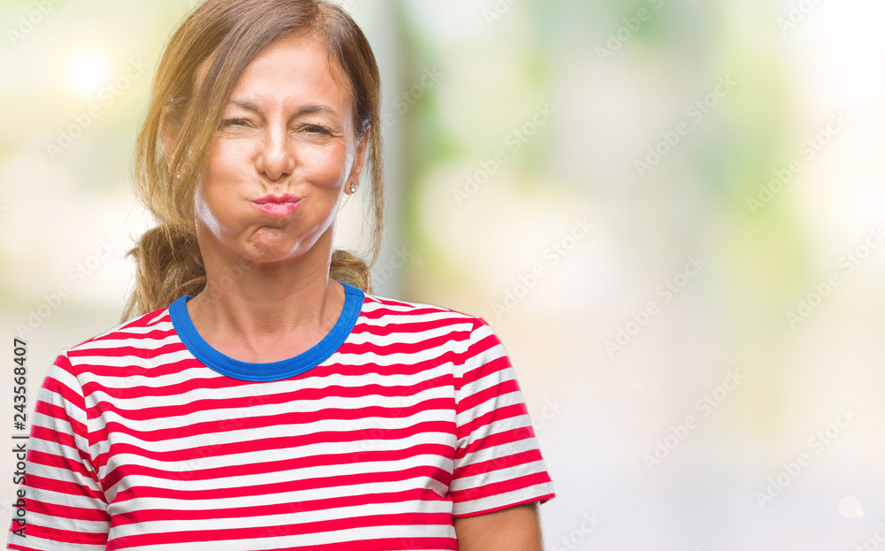 Middle age senior hispanic woman over isolated background puffing cheeks with funny face. Mouth inflated with air, crazy expression.