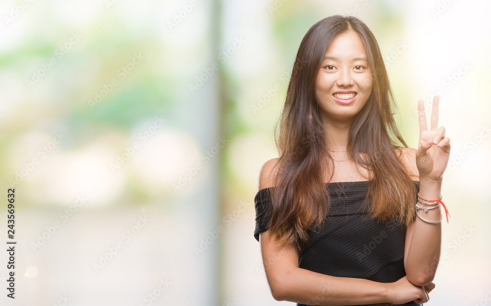 Young asian woman over isolated background smiling with happy face winking at the camera doing victory sign. Number two. Young asian woman over isolated background smiling with happy face winking at the camera doing victory sign. Number two.