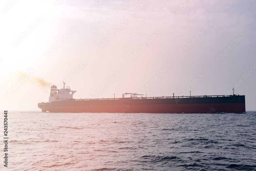 Oil tanker at sea, lit by the sun. Transatlantic transportation.