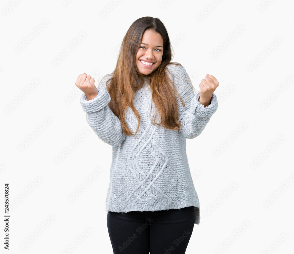 Young beautiful brunette woman wearing sweater over isolated background celebrating surprised and amazed for success with arms raised and open eyes. Winner concept. Young beautiful brunette woman wearing sweater over isolated background celebrating surprised and amazed for success with arms raised and open eyes. Winner concept.