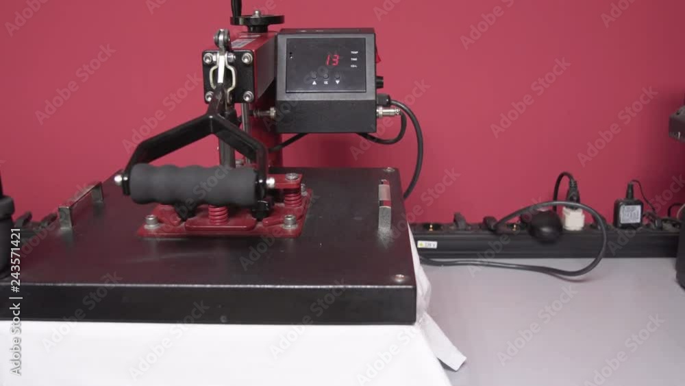 Heat press machine. Man pressing the transfer element on a t-shirt. Dolly shot.