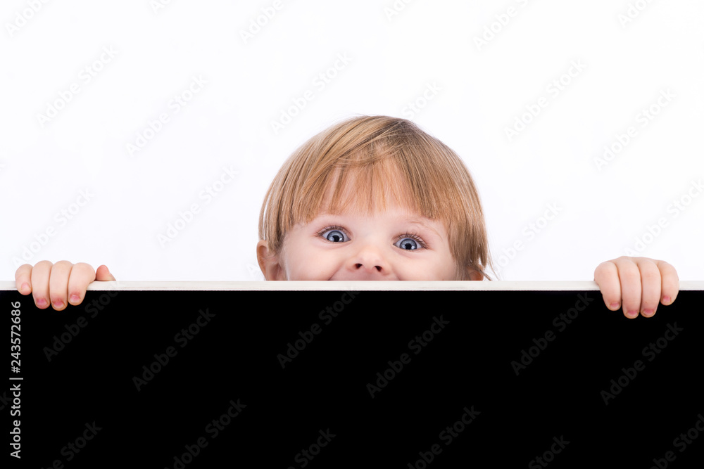 A little girl looks out from behind a black board. Blackboard space for text A little girl looks out from behind a black board. Blackboard space for text