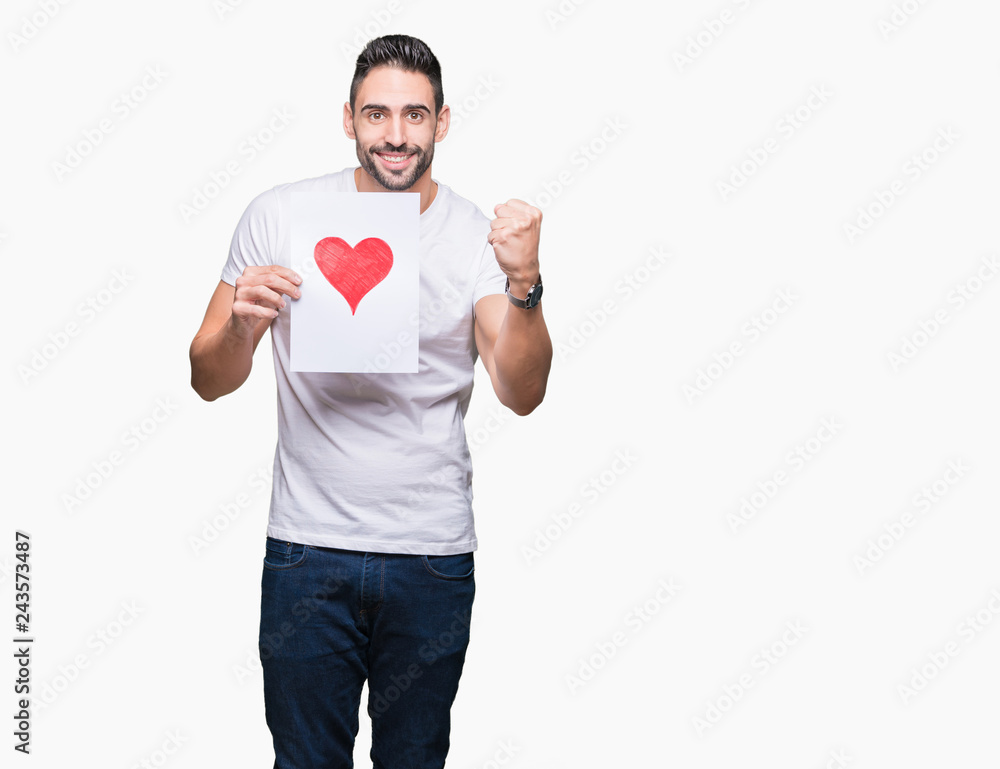 Handsome young man holding card with red heart over isolated background screaming proud and celebrating victory and success very excited, cheering emotion