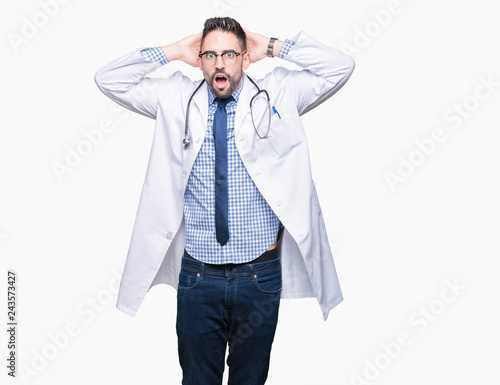 Handsome young doctor man over isolated background Crazy and scared with hands on head, afraid and surprised of shock with open mouth