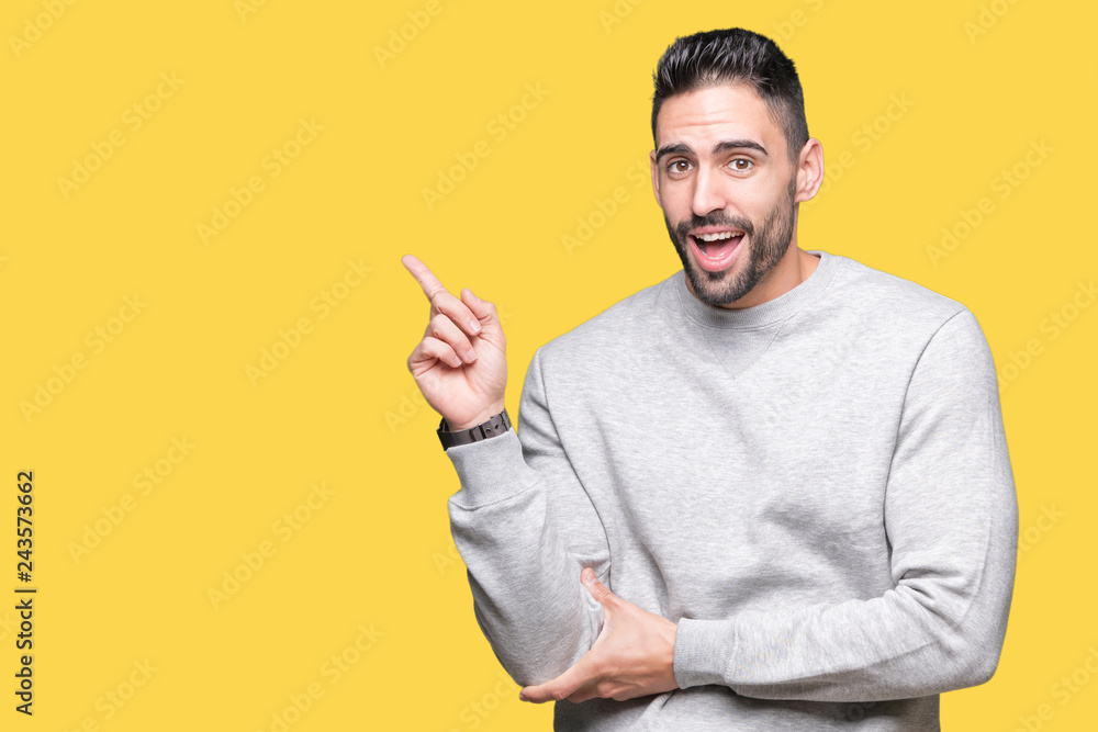 Young handsome man wearing sweatshirt over isolated background with a big smile on face, pointing with hand and finger to the side looking at the camera.