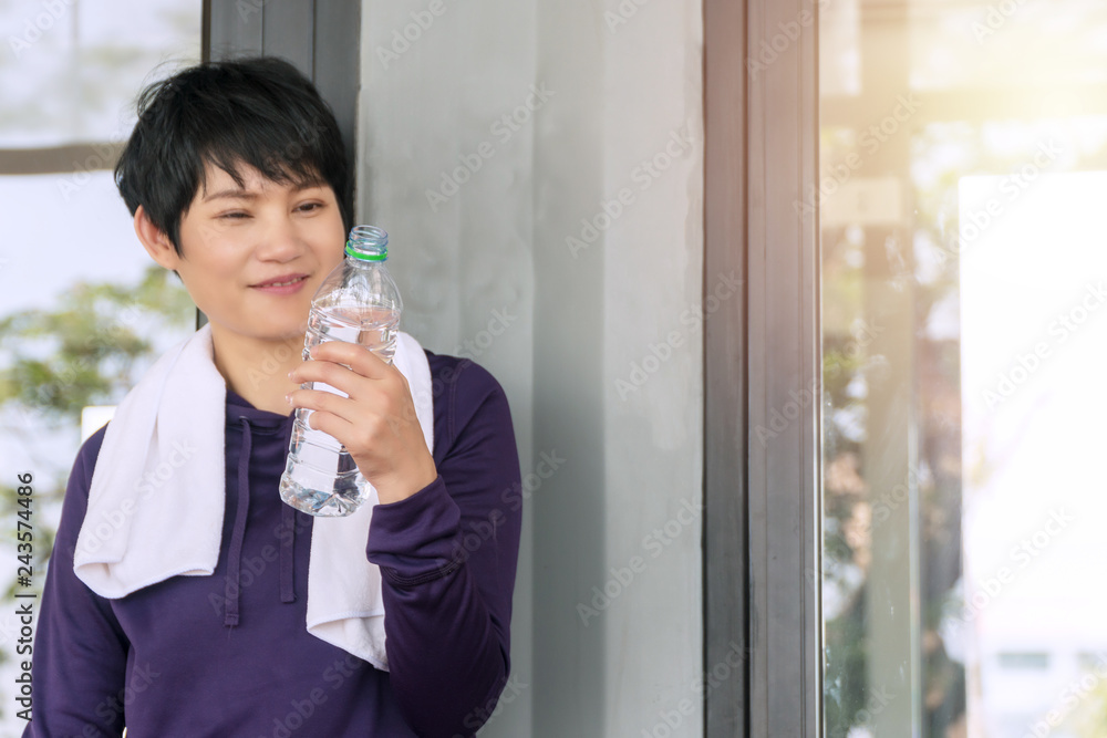 Happy middle-aged woman holding bottle of water after exercise. Sport lifestyle concept. Happy middle-aged woman holding bottle of water after exercise. Sport lifestyle concept.